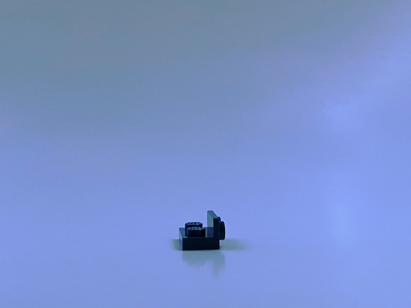 Un piccolo mattone di plastica nero a forma di L si trova su una superficie.