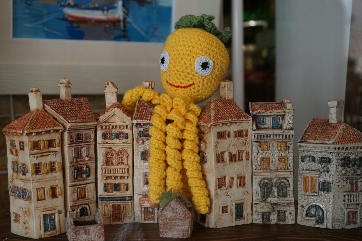 Un giocattolo giallo all'uncinetto si trova dietro casette in ceramica in miniatura.